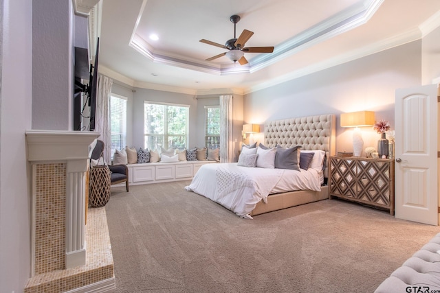 carpeted bedroom featuring ceiling fan, crown molding, and a tray ceiling