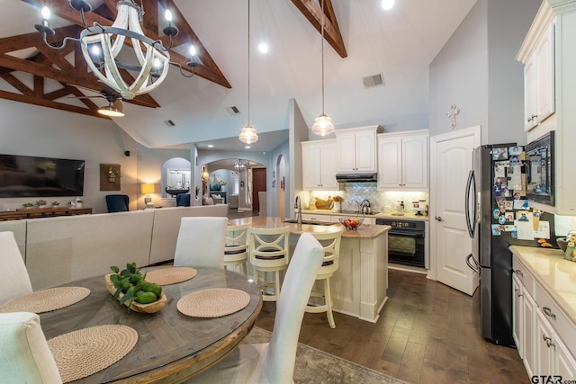 kitchen featuring white cabinetry, a breakfast bar, black appliances, a kitchen island with sink, and dark wood-type flooring