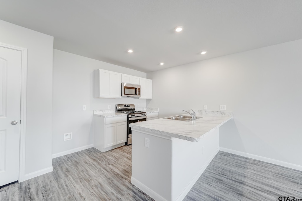 406 Parker Oaks Dr, Chandler, TX 75758 - kitchen featuring stainless steel appliances, a sink, light wood-style flooring, baseboards, and white cabinets