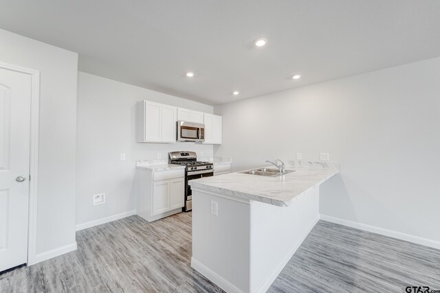 406 Parker Oaks Dr, Chandler, TX 75758 - kitchen featuring stainless steel appliances, a sink, light wood-style flooring, baseboards, and white cabinets