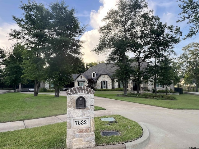7532 Northlake Dr, Tyler, TX 75703 - french country style house featuring stone siding, a front yard, and curved driveway