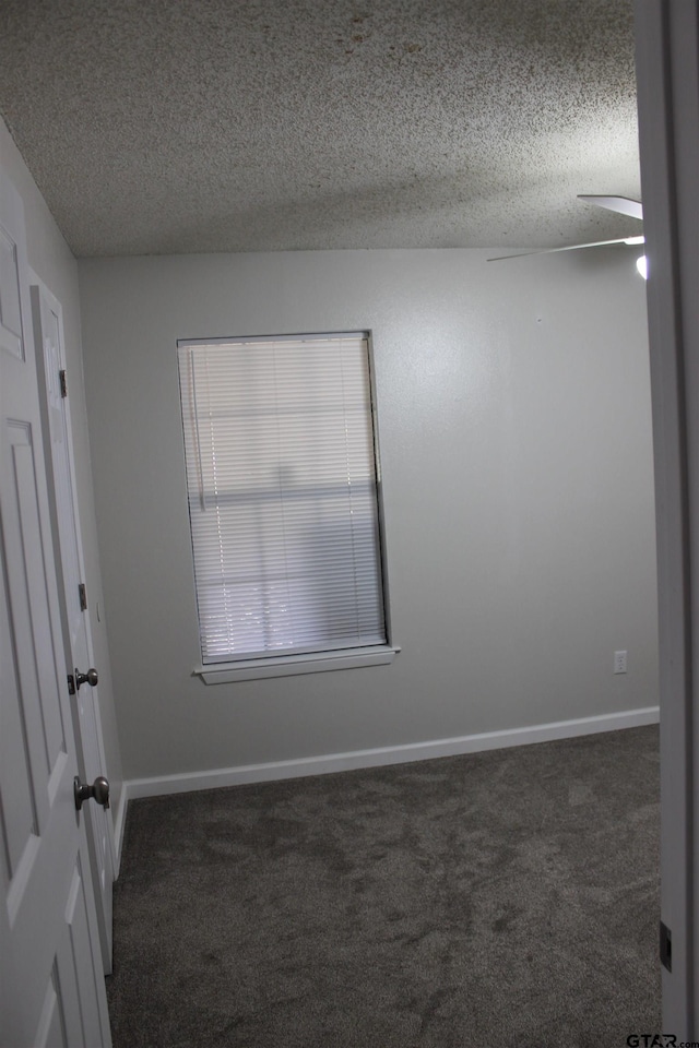 unfurnished room featuring a textured ceiling and dark carpet