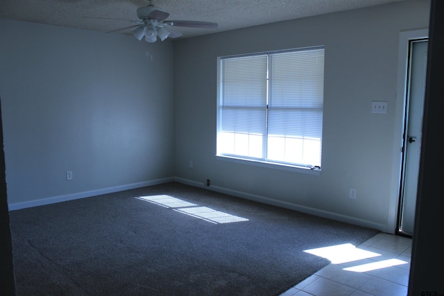 spare room with ceiling fan, a textured ceiling, and light colored carpet