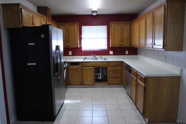 kitchen featuring a textured ceiling, appliances with stainless steel finishes, sink, and light tile patterned floors