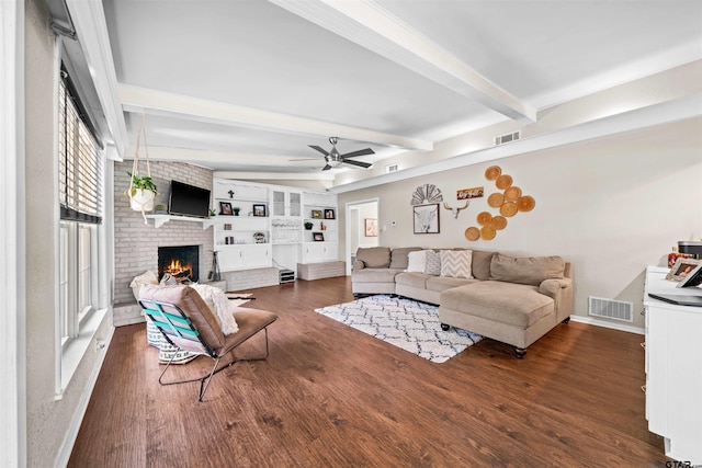 living room featuring a brick fireplace, dark hardwood / wood-style floors, ceiling fan, and beam ceiling