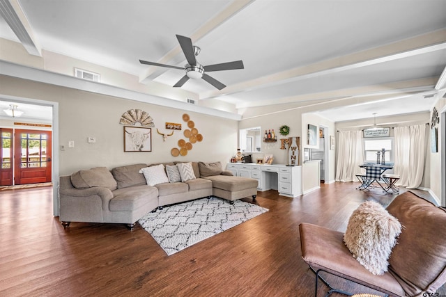 living room featuring dark wood-type flooring, built in desk, ceiling fan, and beam ceiling