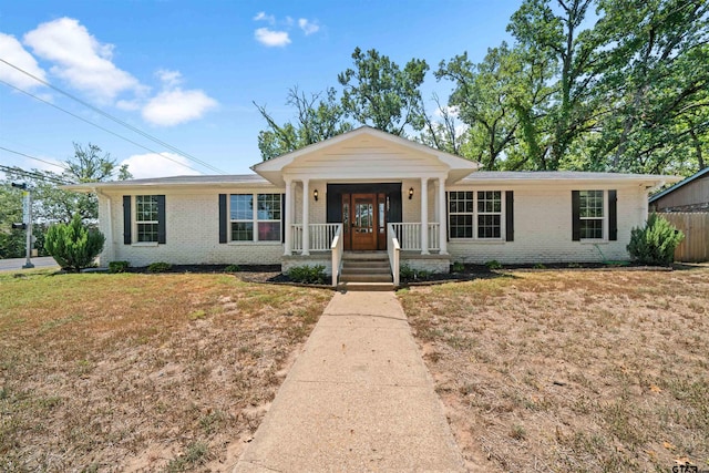 ranch-style home featuring covered porch and a front lawn