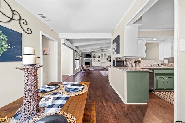 kitchen with stainless steel appliances, green cabinets, dark hardwood / wood-style floors, crown molding, and a fireplace