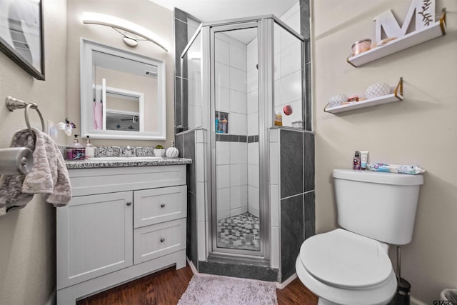 bathroom with hardwood / wood-style floors, walk in shower, vanity, and toilet