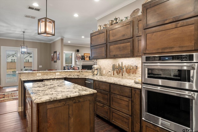 kitchen with kitchen peninsula, hanging light fixtures, stainless steel double oven, crown molding, and decorative backsplash