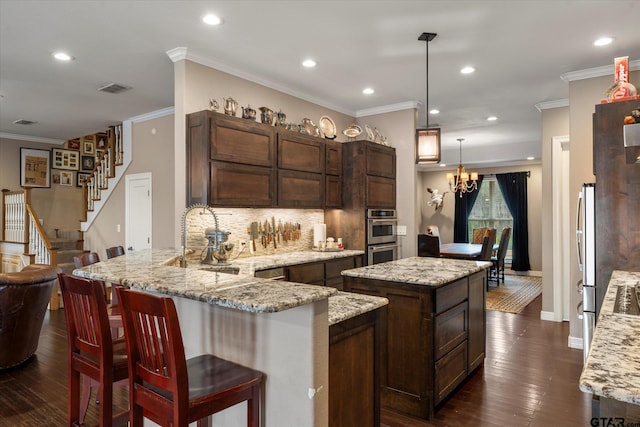 kitchen featuring pendant lighting, crown molding, tasteful backsplash, and kitchen peninsula