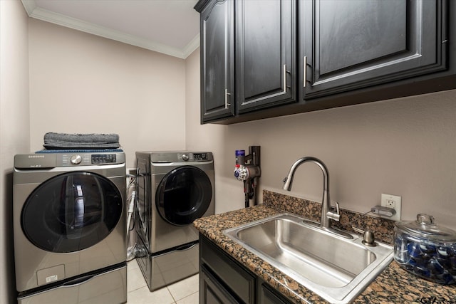 clothes washing area featuring washing machine and dryer, sink, light tile patterned floors, cabinets, and ornamental molding