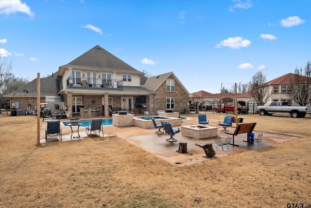 back of house with a yard, a fire pit, a balcony, a pool with hot tub, and a patio