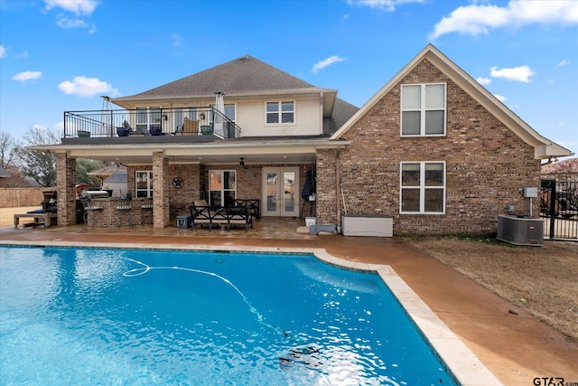 back of house featuring a fenced in pool, a patio, central air condition unit, and a balcony