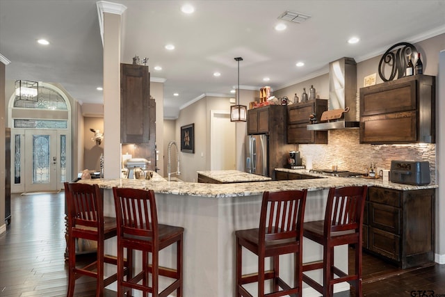 kitchen with appliances with stainless steel finishes, sink, tasteful backsplash, and wall chimney range hood