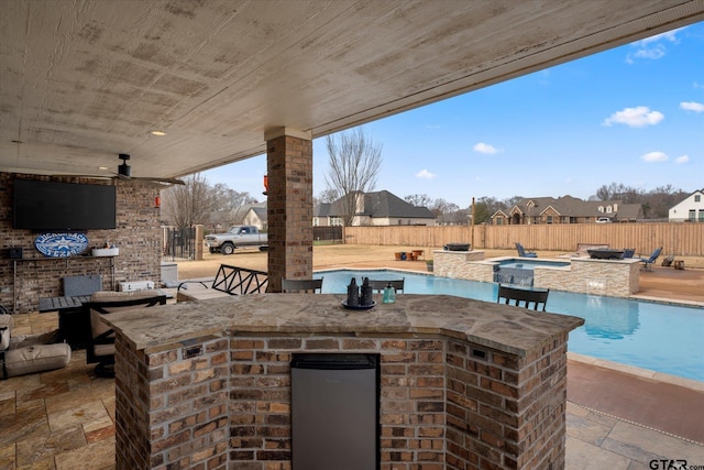 view of patio featuring an outdoor bar, ceiling fan, exterior kitchen, and a swimming pool with hot tub