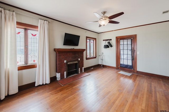 unfurnished living room with light wood finished floors, a ceiling fan, crown molding, a fireplace, and baseboards