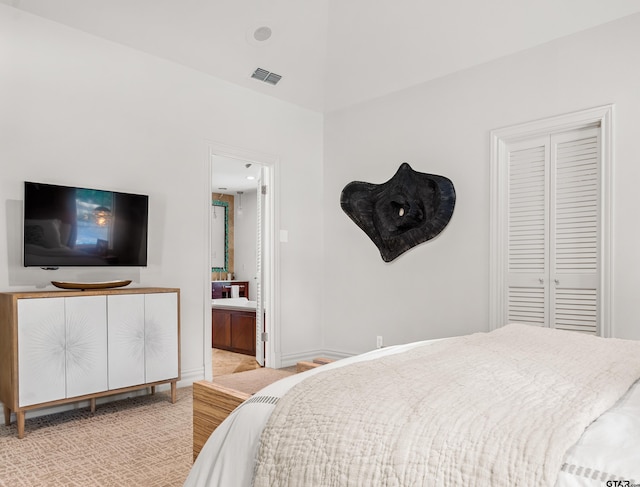 bedroom with light colored carpet, connected bathroom, and a closet