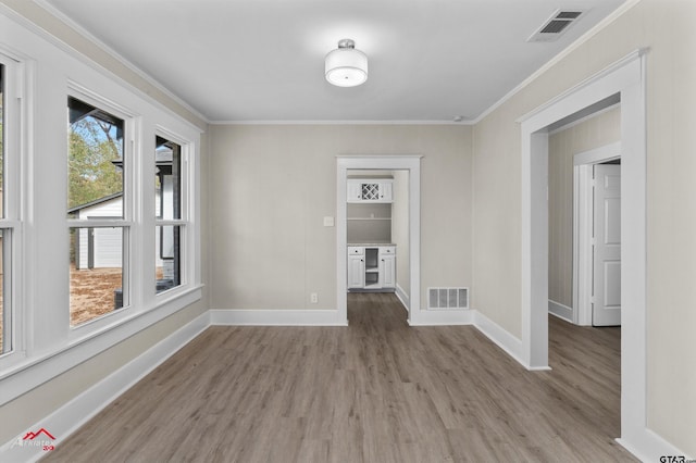 spare room featuring light wood-type flooring and crown molding