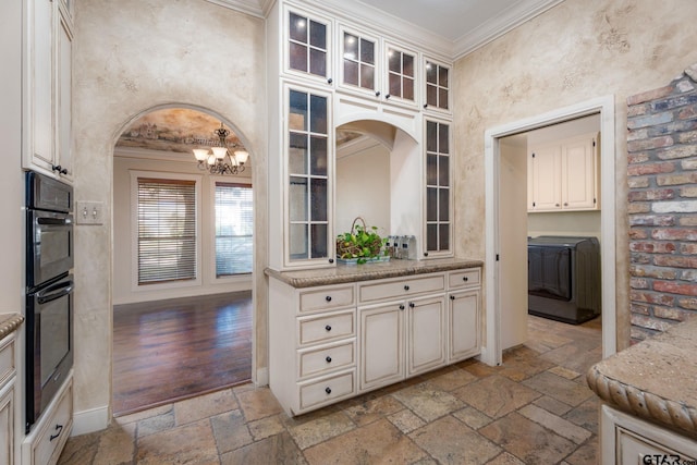 kitchen with light stone counters, washer / dryer, light hardwood / wood-style flooring, and crown molding