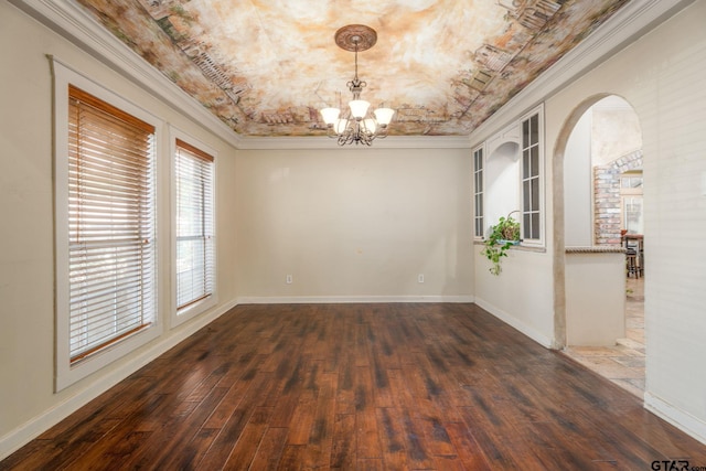 spare room with dark hardwood / wood-style flooring, a raised ceiling, crown molding, and an inviting chandelier