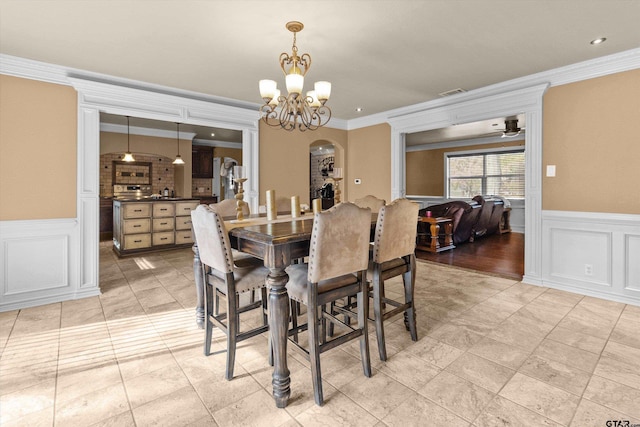 dining space with ceiling fan with notable chandelier and ornamental molding