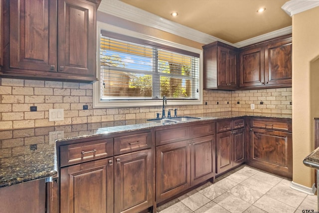 kitchen with decorative backsplash, ornamental molding, sink, and dark stone counters