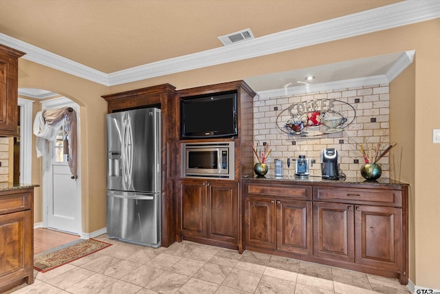 kitchen with dark stone countertops, crown molding, and stainless steel appliances