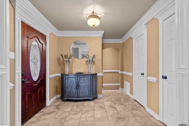 foyer with a textured ceiling and crown molding