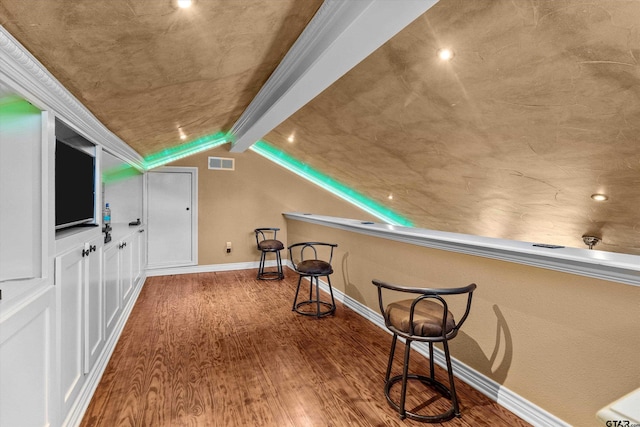 bonus room with hardwood / wood-style floors and vaulted ceiling with beams