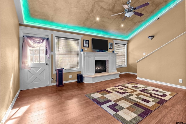 unfurnished living room featuring hardwood / wood-style floors, ceiling fan, and a tray ceiling