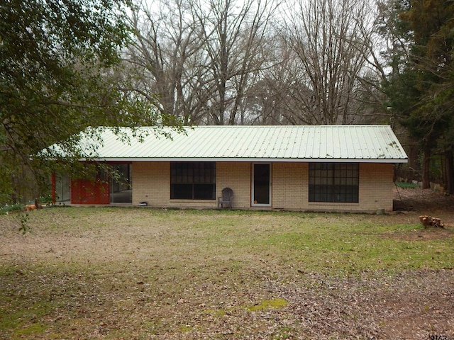 view of front of home featuring a front yard, metal roof, and brick siding