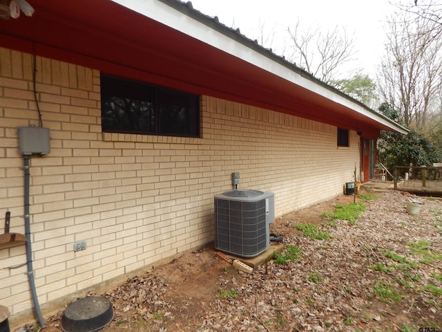 view of side of home featuring brick siding and central air condition unit