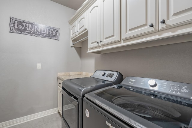 clothes washing area featuring light tile patterned flooring, cabinets, and washing machine and dryer