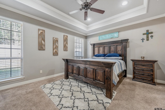 carpeted bedroom featuring ceiling fan, multiple windows, and a tray ceiling