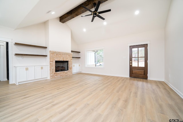 unfurnished living room with light wood finished floors, a wealth of natural light, a ceiling fan, and beamed ceiling