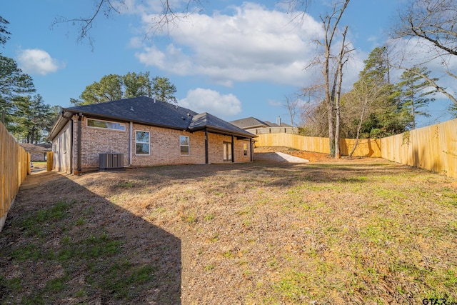 back of property with central air condition unit, brick siding, a lawn, and a fenced backyard
