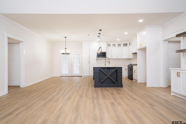 kitchen featuring crown molding, white cabinetry, stainless steel microwave, light countertops, and gas stove