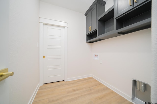 laundry room with baseboards, hookup for a washing machine, light wood finished floors, and cabinet space