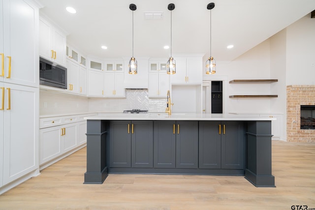 kitchen with white cabinetry, light countertops, built in microwave, and light wood-style floors