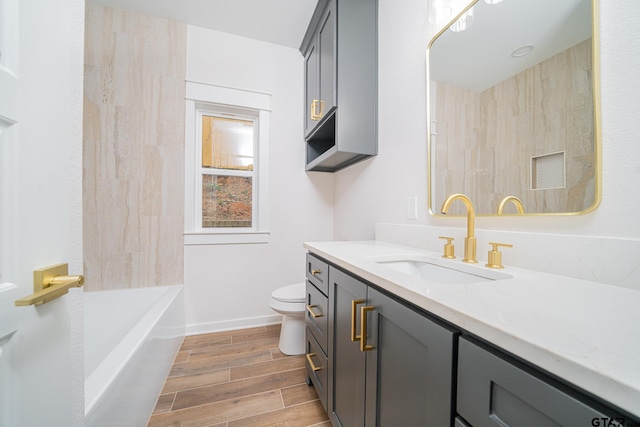 bathroom featuring vanity, wood finish floors, baseboards, and toilet