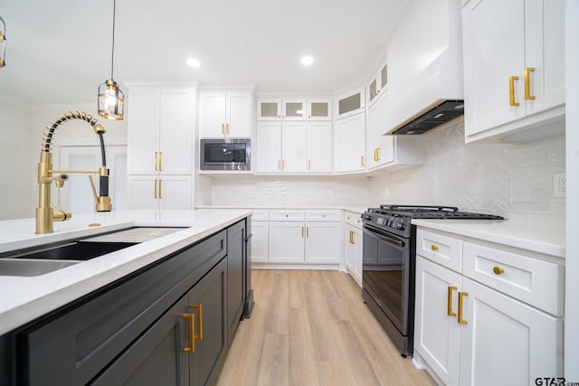 kitchen with white cabinetry, stainless steel microwave, gas stove, and a sink