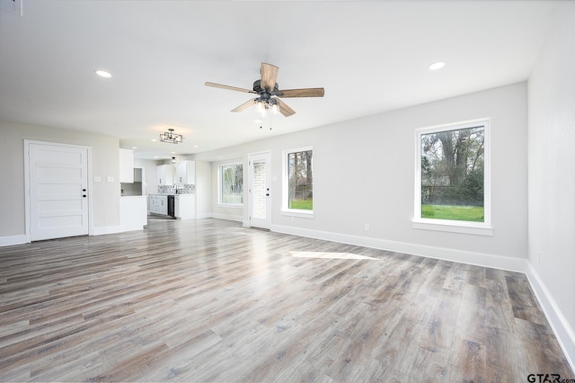 unfurnished living room featuring recessed lighting, a wealth of natural light, and baseboards