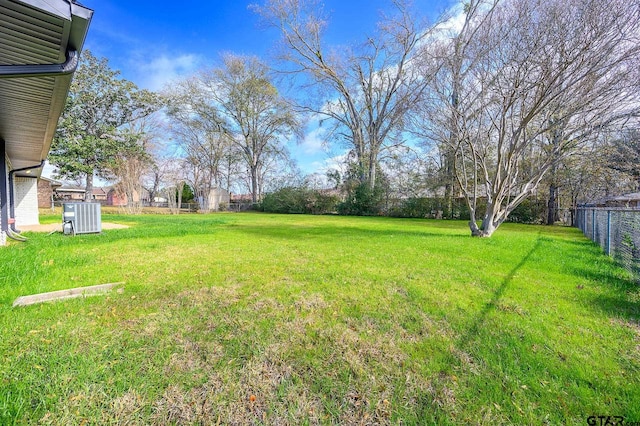 view of yard with central AC and fence