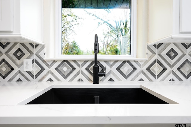 details featuring white cabinets, tasteful backsplash, and a sink