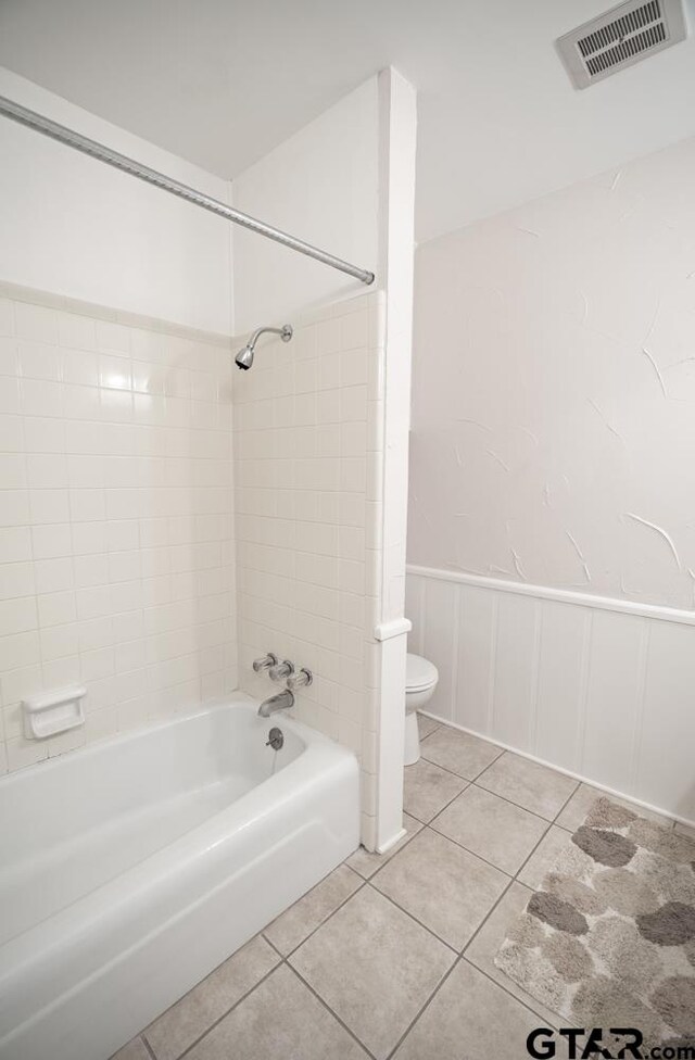 bathroom with tile patterned flooring, toilet, and tiled shower / bath