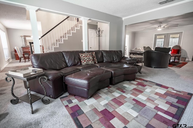 living room with french doors, a textured ceiling, decorative columns, carpet, and ceiling fan