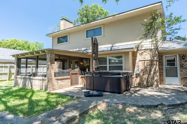 back of house with a hot tub, a sunroom, and a yard