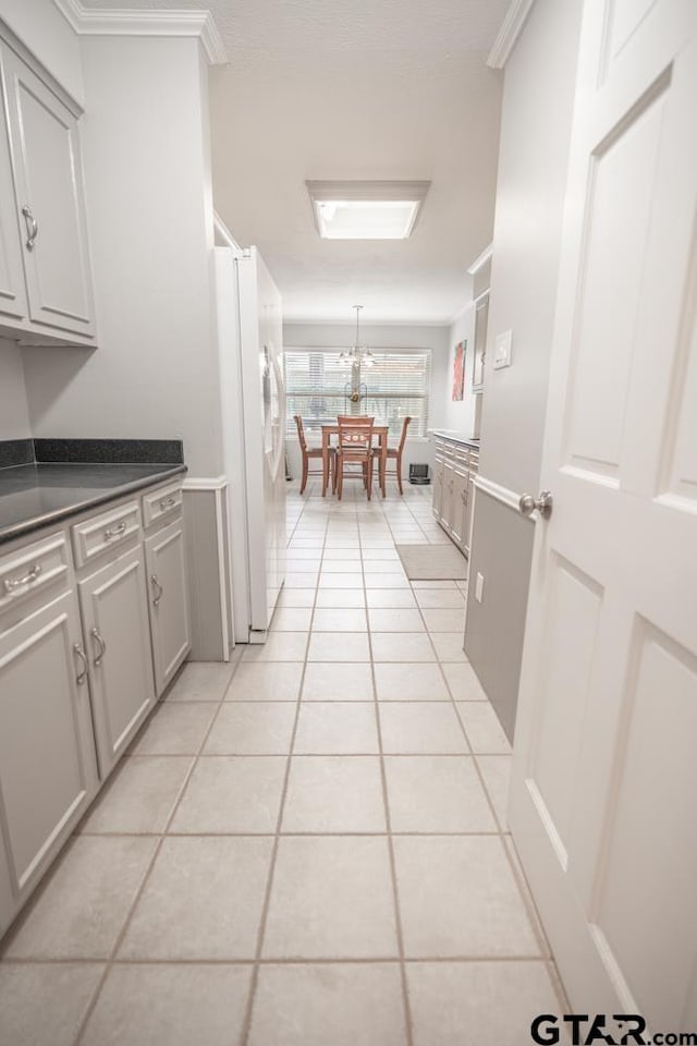 kitchen with gray cabinetry, light tile patterned floors, crown molding, and white fridge