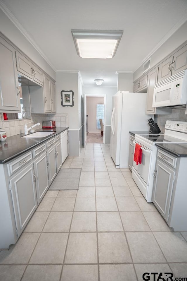 kitchen with gray cabinetry, backsplash, light tile patterned floors, sink, and white appliances